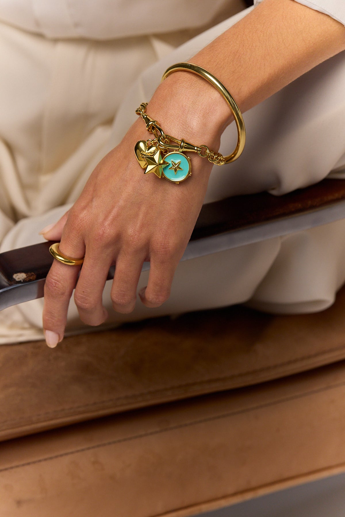 Gold charm bracelet with heart, star, and blue round charm on wrist