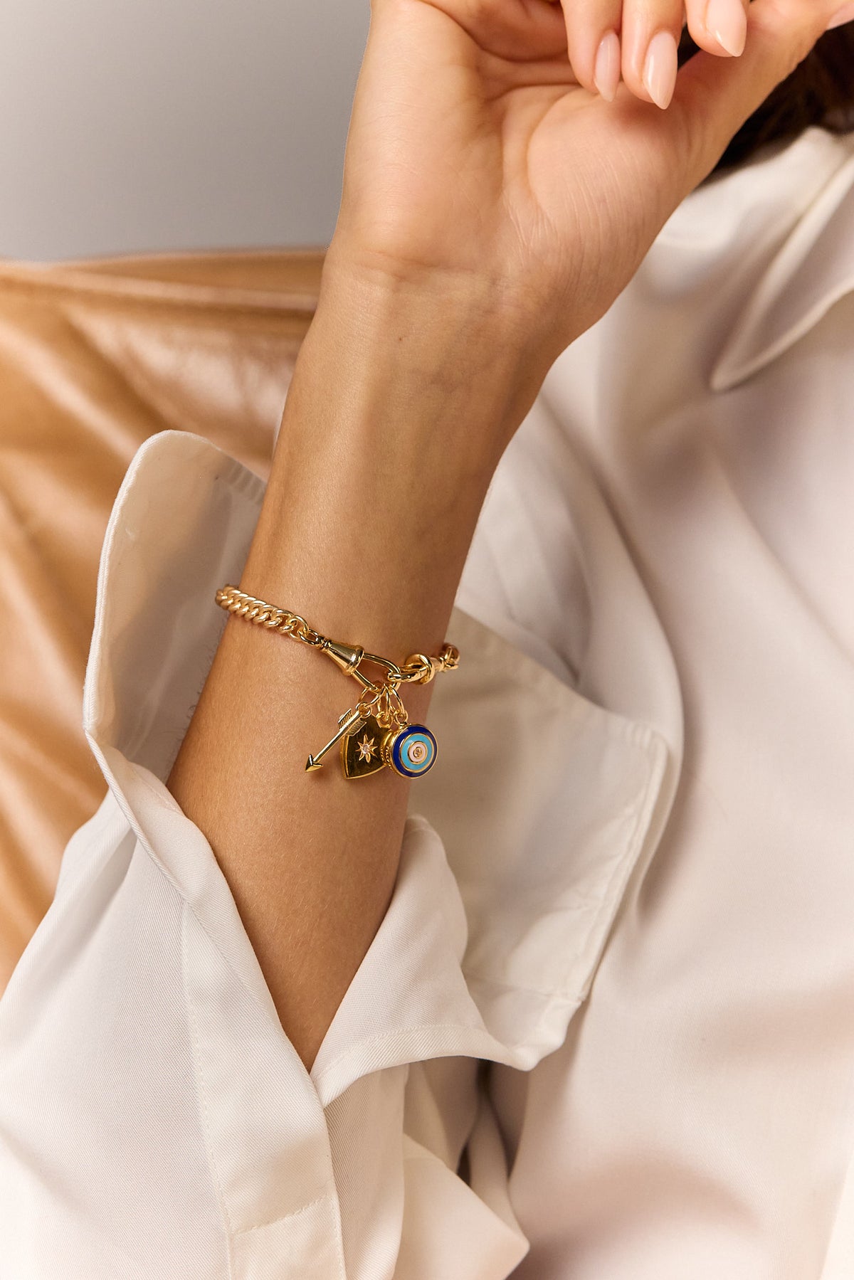 Gold charm bracelet with blue eye and dangling key and heart charms