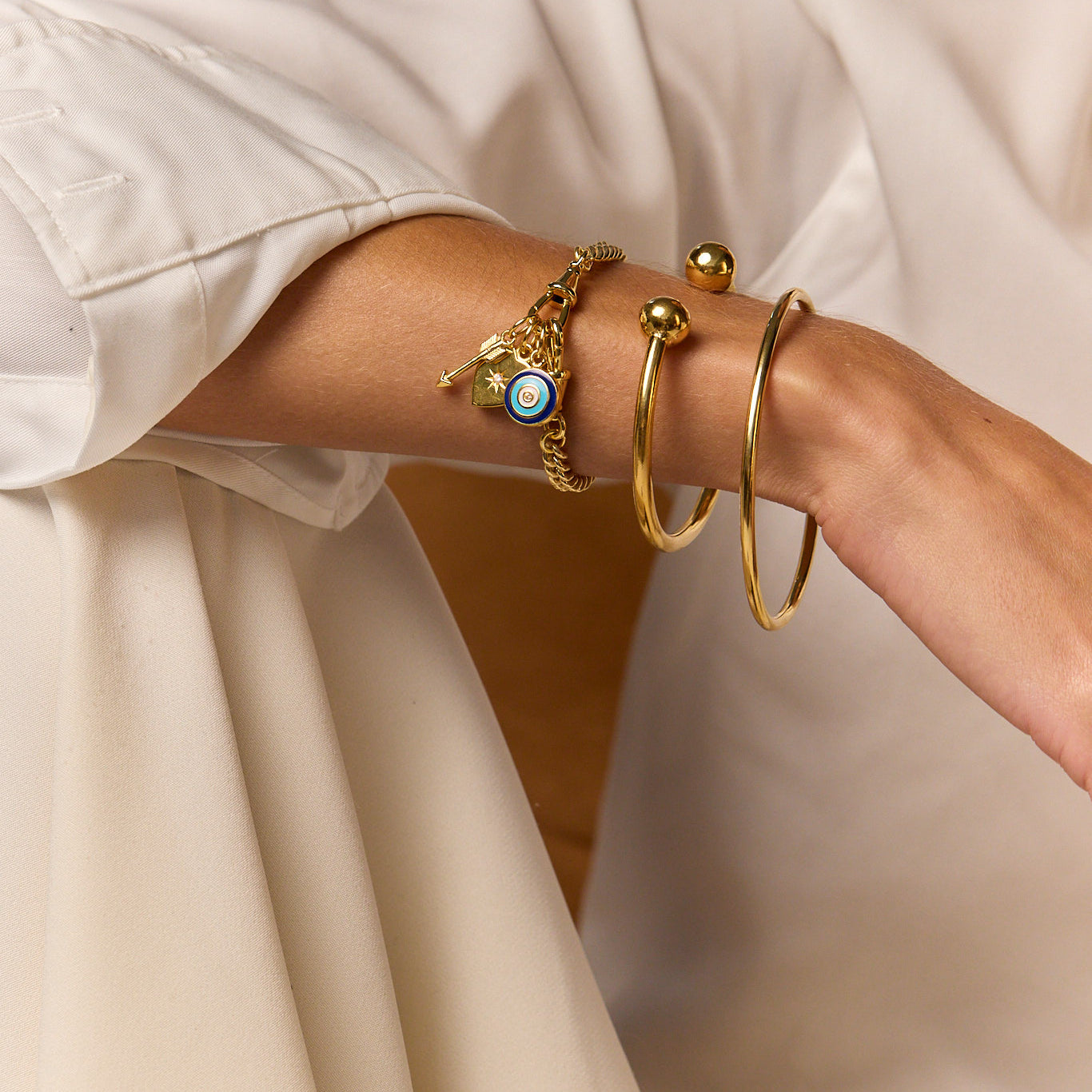 Gold charm bracelet with blue eye charm and dangling key and star charms