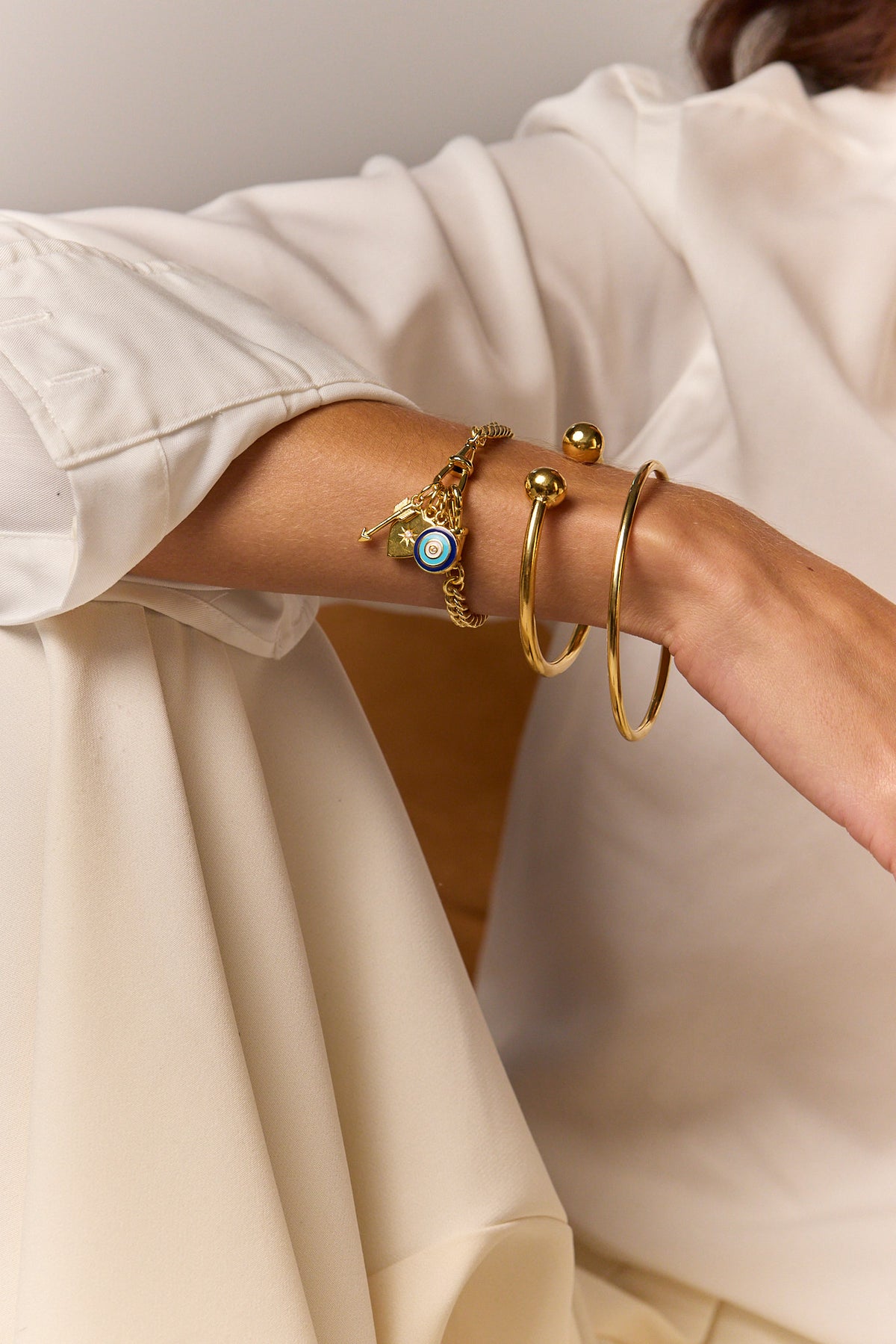 Gold charm bracelet with blue eye charm and dangling key and star charms