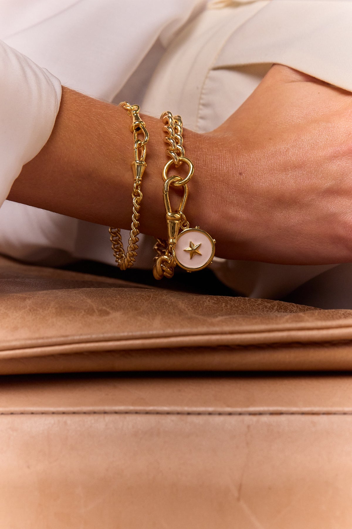 Gold chain bracelet set with round star charm on wrist