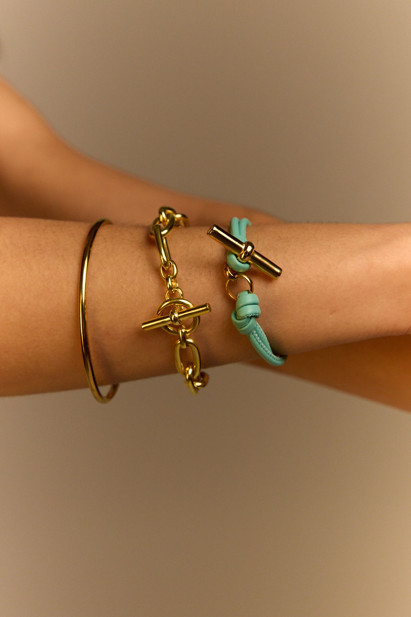 Aquamarine leather bracelet with gold T-bar charm and knot clasp on wrist