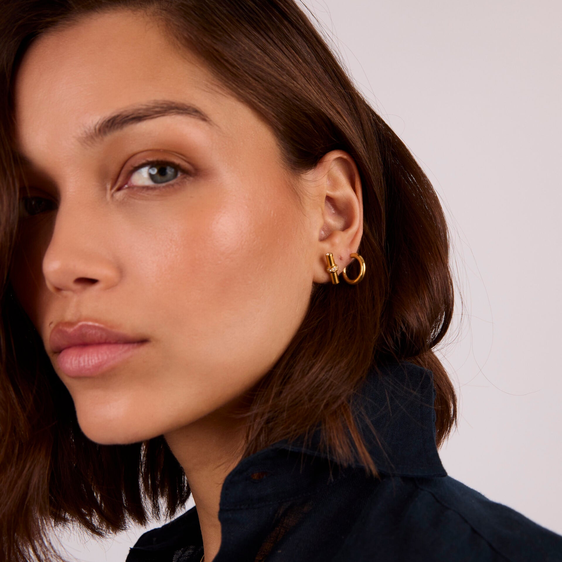 Gold T-bar stud earrings with clear crystals on model's ear
